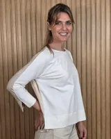Remerón de manga larga blanco en el frente y mangas, con la parte posterior en color beige. Presenta cuello redondo y diseño holgado con aberturas laterales en el dobladillo.