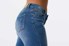 Jeans de corte ajustado y tiro medio en color azul, con detalles de bordados florales coloridos en una de las piernas.