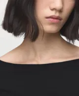 Camiseta negra de manga larga entallada, con diseño de cuello barco y puños ligeramente acampanados.