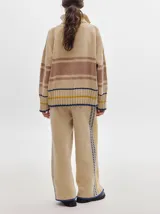 Pantalón de punto con textura tipo terciopelo, de corte ancho y holgado. Presenta cintura elástica con cordón de ajuste y detalle de pespuntes decorativos en los laterales.