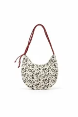 Cartera de hombro con diseño de media luna, confeccionada en tela con estampado animal print en tonos blanco y negro. Cuenta con una correa larga de cuerda trenzada en color bordó con detalle de nudo ajustable.