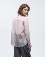 Camisa negra combinada bicolor confeccionada en telas italianas, de silueta holgada. Tiene cuello camisero, cartera con botones, y un bolsillo plaqué. Las mangas largas presentan pliegues en los puños y tablitas en la espalda.