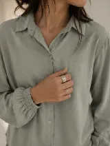 Camisa de diseño clásico con cuello camisero, mangas largas con puño elastizado y cierre de botones al frente.