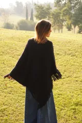 Poncho tejido en lana merino color marrón, con diseño de punto acanalado y terminación con flecos en el borde inferior. Incluye una pequeña etiqueta de cuero en la parte posterior.