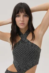 Vestido tejido calado plateado, con escote halter, cut outs en el abdomen y falda larga con tajo lateral.