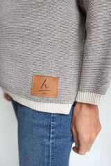 Buzo oversize tejido con diseño jacquard de un grifo en la espalda y detalles geométricos en las mangas. Presenta cuello redondo y puños acanalados.