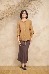Campera color beige de lino, con cuello mao, mangas 3/4 con botón para sujetar, cierre frontal con botones y ajuste con cordón en la cintura.