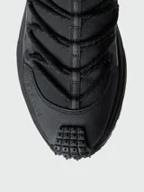 Championes Moncler modelo Trailgrip Lite2 de color negro, diseñados para trekking y actividades al aire libre. Presentan una silueta robusta, suela dentada Vibram, cordones redondos gruesos, tiradores en la lengüeta y el talón, y el nombre de la marca grabado en el lateral.