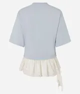 Remera overboxy de algodón color celeste, con cuello redondo, mangas cortas amplias y bajo asimétrico con aplicación de encaje blanco.