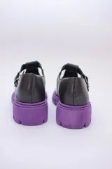 Guillermina de cuero negra con suela tractorada roja y hebilla dorada.