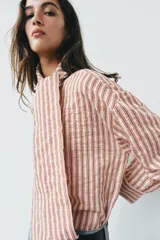 Camisa de rayas rojas y blancas, cuello redondo con lazada integrada y manga larga.