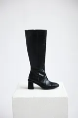 Bota bucanera de caña alta confeccionada en cuero con textura de cocodrilo, cuenta con cierre lateral y taco cuadrado.