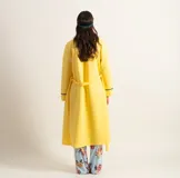 Bata clásica amarilla con textura capitoné y ribete verde en cuello, solapa, puños y cinturón.