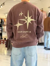 Buzo oversize de cuello redondo en color marrón con efecto gastado, con gran estampado en la espalda de estrellas y el texto VCP CNPT.