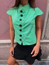Top verde a cuadros con patrón de rayas y líneas azules y blancas, diseño entallado con mangas cortas abanicadas, cuello mao y cierre frontal con grandes botones negros esféricos.