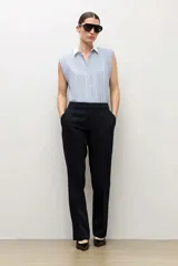 Camisa sin mangas celeste con rayas verticales blancas y finas líneas oscuras, con cuello camisero blanco y cierre frontal de botones.