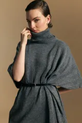 Poncho de tejido de punto color gris, con cuello alto y mangas amplias de diseño holgado.