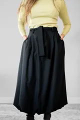 Pollera midi de corte balloon, color negro, confeccionada en gabardina. Presenta un diseño de cintura alta con lazo ajustable y ruedo con volumen.