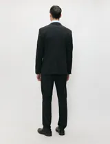 Ambo slim fit negro confeccionado en tejido tecnológico elastizado, compuesto por blazer estructurado y pantalón de vestir de corte recto.