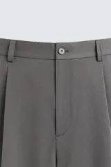 Bermuda de corte relajado color negro, con pliegues frontales, cierre de cremallera y botón, bolsillos laterales y bolsillos traseros.