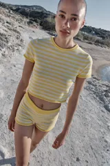 Top corto de punto con diseño a rayas horizontales en color amarillo y blanco, cuello redondo y manga corta.