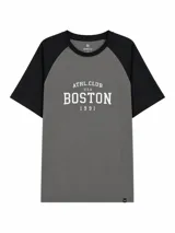 Remera de estilo deportivo con mangas raglán en color negro y cuerpo en color gris. Presenta un estampado frontal con la inscripción 'ATHL. CLUB U.S.A. BOSTON 1991' en color blanco.