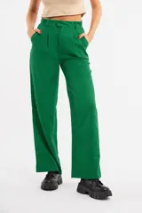 Pantalón de vestir estilo sastrero color verde, de corte recto y tiro alto. Presenta pretina con trabillas, cierre frontal con botón y pinzas en la parte superior.