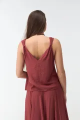 Musculosa bordó de tejido satinado, con escote en V y breteles con detalle de nudos en los hombros.