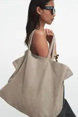 Bolso tipo maxi shopper confeccionado en serraje, con diseño minimalista y doble asa de hombro. Cuenta con un compartimento principal amplio y un bolsillo interior con cierre.