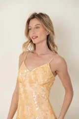 Vestido corto color naranja pastel, de tul bordado con lentejuelas, breteles finos y corte debajo del busto.