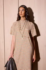 Vestido midi de algodón con diseño a rayas horizontales en color marrón y blanco. Presenta un corte holgado, cuello redondo, mangas cortas con hombros caídos y un pequeño bolsillo frontal en el pecho.
