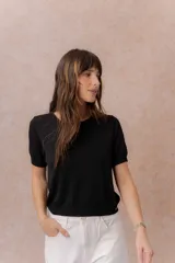 Remera tejida de punto fino en color negro, de manga corta, con escote redondo y terminaciones en rib en el cuello, mangas y ruedo.