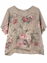 Blusa de lino color beige con estampado floral en tonos rosados y grises, corte holgado, mangas cortas y detalles de costuras caladas en el frente y las mangas.