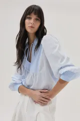 Blusa celeste a rayas verticales blancas, con cuello mao con lazos, mangas abullonadas y corte imperio.