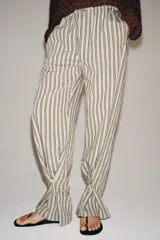 Pantalón de tiro medio con diseño de rayas verticales, confeccionado en mezcla de viscosa. Presenta cintura elástica ajustable con cordones, bolsillos laterales ocultos y pierna recta con bajo ajustable mediante botón.