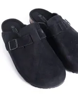 Zuecos cerrados al frente color negro, confeccionados en material símil gamuza. Presentan una tira ajustable con hebilla metálica en el empeine y una suela con detalle de corcho en el talón.