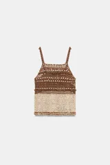 Top de crochet con escote recto y tirantes finos. Presenta un diseño bicolor con la parte superior en color marrón y la parte inferior decorada con abalorios en tonos crema y marrón.