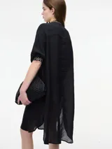 Vestido túnica camisera color negro con botones en la parte delantera, cuello mao y detalle de bordado en el pecho y mangas. Presenta tajos verticales laterales.