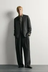 Blazer relaxed fit de color negro, confeccionada en tejido fluido con mezcla de viscosa y lino. Presenta cuello sin solapas, manga larga, bolsillos de solapa en la cadera y cierre frontal de un botón.