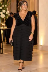 Vestido midi negro con escote en V, cuerpo de terciopelo y falda de crepe con múltiples volados horizontales superpuestos.