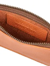 Sobre de cuero naranja con textura graneada, cierre metálico superior y correa de mano en el lateral. Cuenta con el logo de la marca grabado en la parte frontal.