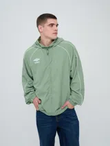 Campera rompevientos Umbro modelo Venti, de color verde con capucha y cierre frontal completo. Presenta detalles de líneas blancas a lo largo de las mangas y hombros, y el logo de la marca bordado en el pecho.