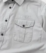 Camisa verde militar de manga larga en sarga de algodón, con cuello clásico, cierre frontal abotonado y dos bolsillos con solapa abotonada en el pecho.