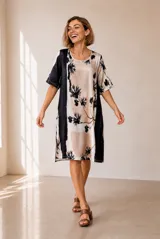 Vestido corto de corte recto y holgado, con mangas cortas y cuello redondo. Presenta un diseño estampado con bloques de color en tonos azul, blanco y negro, con detalles florales.
