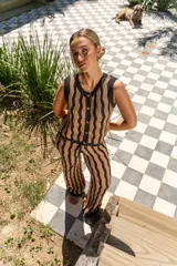 Pantalón tejido de corte recto y tiro alto, con diseño de rayas verticales onduladas en colores beige y negro. Presenta una cintura elástica con cordón ajustable.