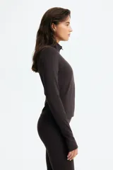 Campera deportiva de manga larga con cierre frontal completo y cuello alto, color marrón oscuro, confeccionada en tejido elástico con tecnología SoftMove y DryMove. Cuenta con mangas largas con aberturas para los pulgares en los puños.