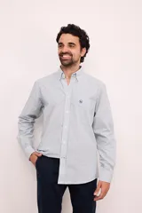 Camisa de corte clásico confeccionada en algodón, con diseño de rayas verticales finas en tonos claros. Presenta cuello con botones, bolsillo frontal en el pecho con logo bordado y mangas largas con puños abotonados.