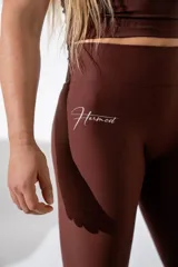 Calza deportiva de tiro alto color marrón, confeccionada en tejido técnico elástico con ajuste ceñido al cuerpo.