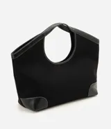 Cartera shopper grande de color negro, confeccionada en poliéster con detalles en material sintético en las esquinas inferiores y en las asas integradas. Cuenta con costuras pespunteadas a contratono y una estructura amplia con abertura superior con cierre.