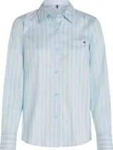 Camisa de manga larga Tommy Hilfiger confeccionada en popelina de algodón, con diseño de rayas verticales en tonos azul claro y blanco. Presenta cuello camisero clásico, cierre frontal con botones y un bolsillo de parche en el pecho con el logo de la marca bordado.